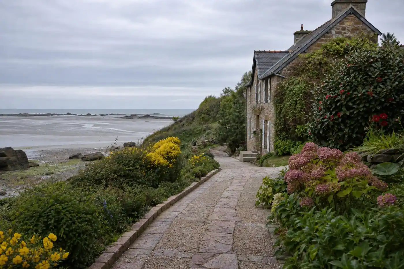 Photo d'une allée de jardin en granit rose et gravier stabilisé menant à une maison de Saint-Brieuc, bordures nettes et pente douce, lumière humide de bord de mer.